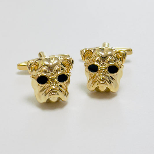 A pair of golden cufflinks shaped like stylized bulldog heads with black detailing for the eyes.