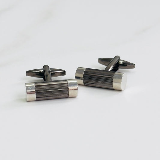 A pair of cylindrical silver cufflinks with a ribbed texture in the middle section.